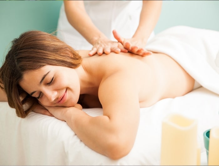 Mujer recibiendo un masaje sobre toalla blanca