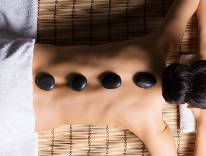 Mujer con piedras de masaje en la espalda